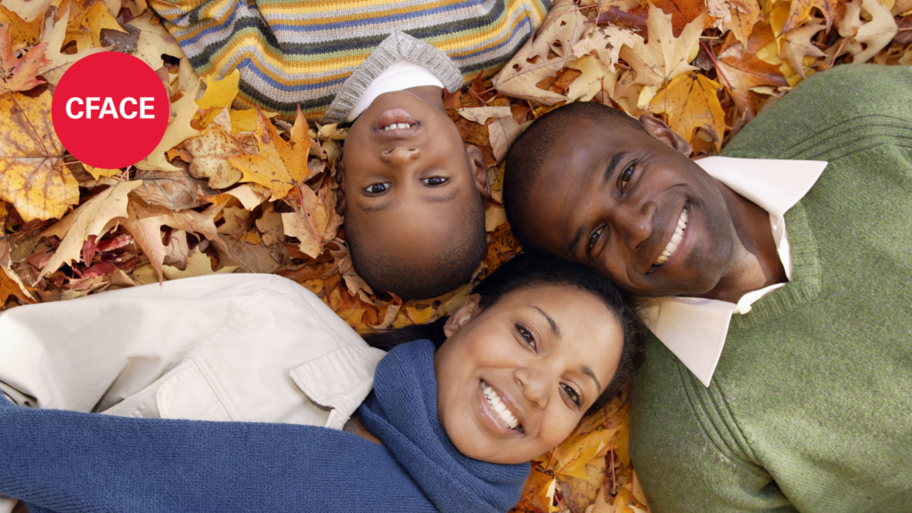 Shows a happy family sitting in fall leaves to demonstrate the point of the page (share family-friendly fall activities). 